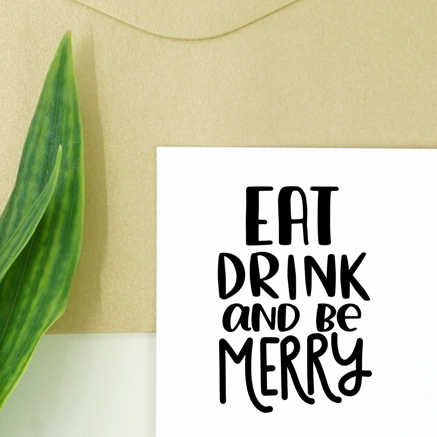 Festive rubber stamp design with Eat, Drink and Be Merry in bold black lettering for holiday cards and crafts.