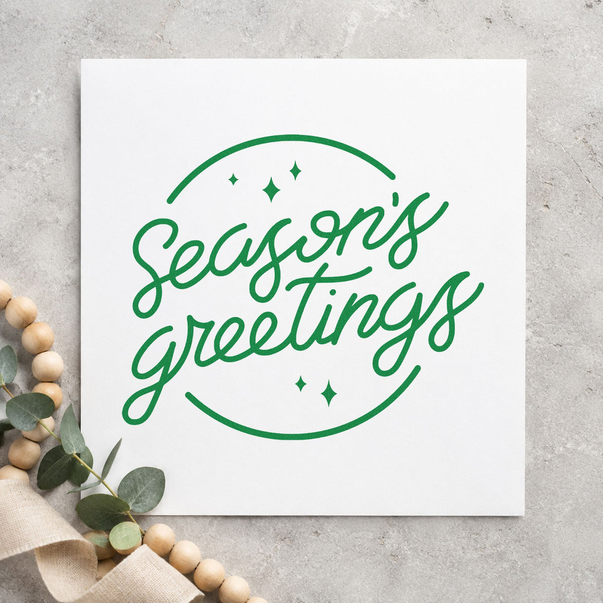 Season's Greetings Circle craft stamp imprinted in green ink on paper, a design suited to envelope flap seals.