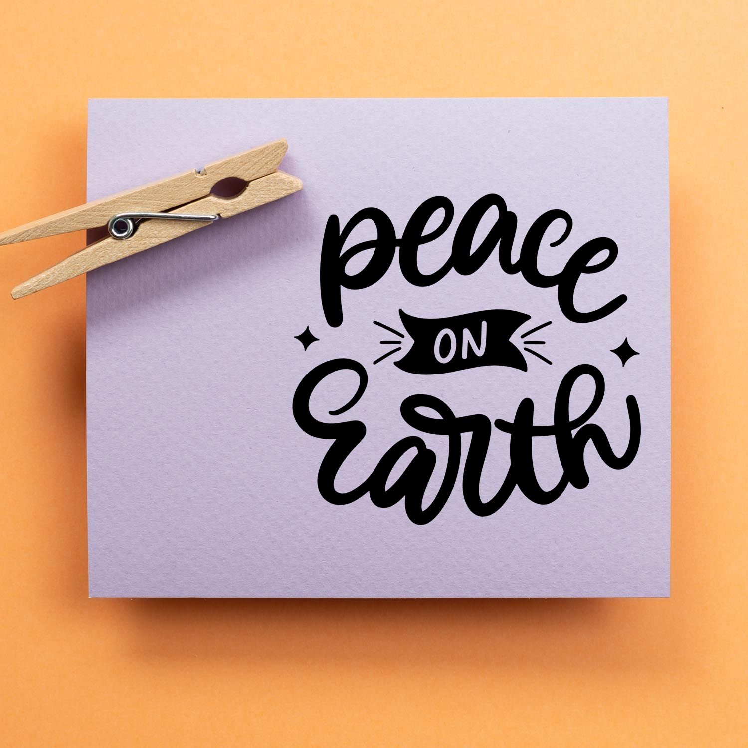 Peace on Earth rubber stamp design on lavender paper with a wooden clothespin