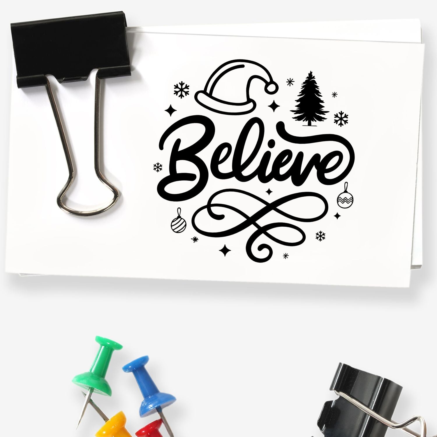 Christmas rubber stamp design with Believe script, Santa hat, tree, ornaments, and snowflakes for holiday cards.