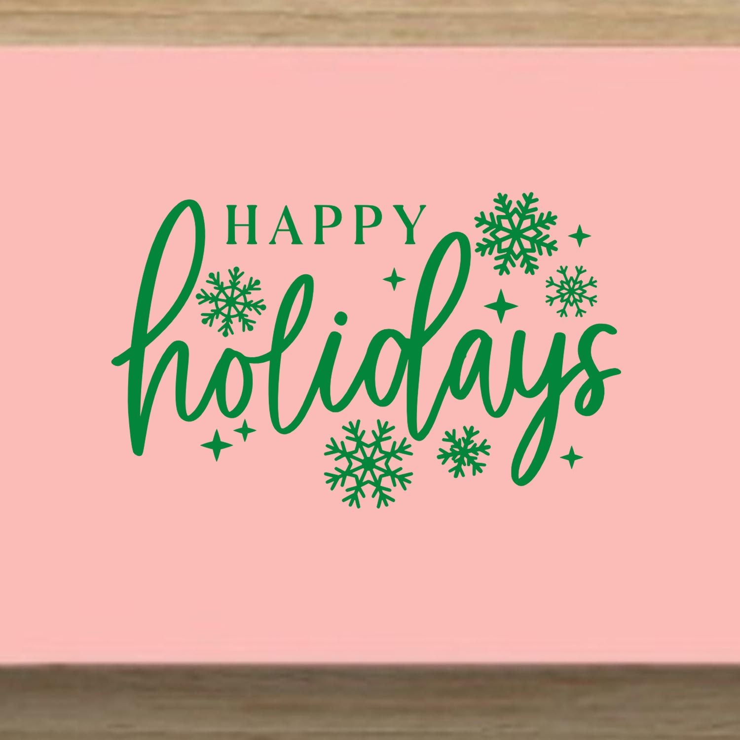 Happy Holidays rubber stamp design with green lettering and snowflakes on a pink background.
