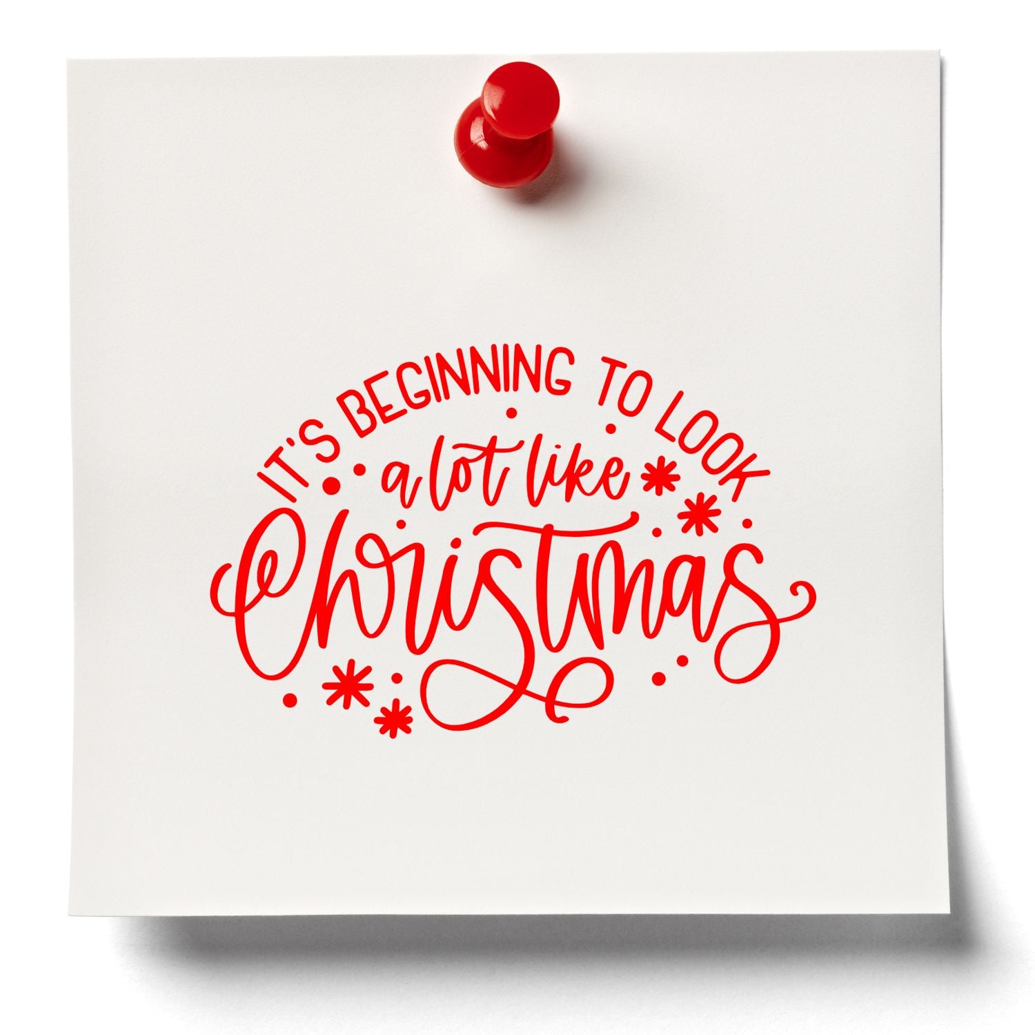 Christmas rubber stamp design with red lettering reading Its Beginning to Look a Lot Like Christmas on white paper.
