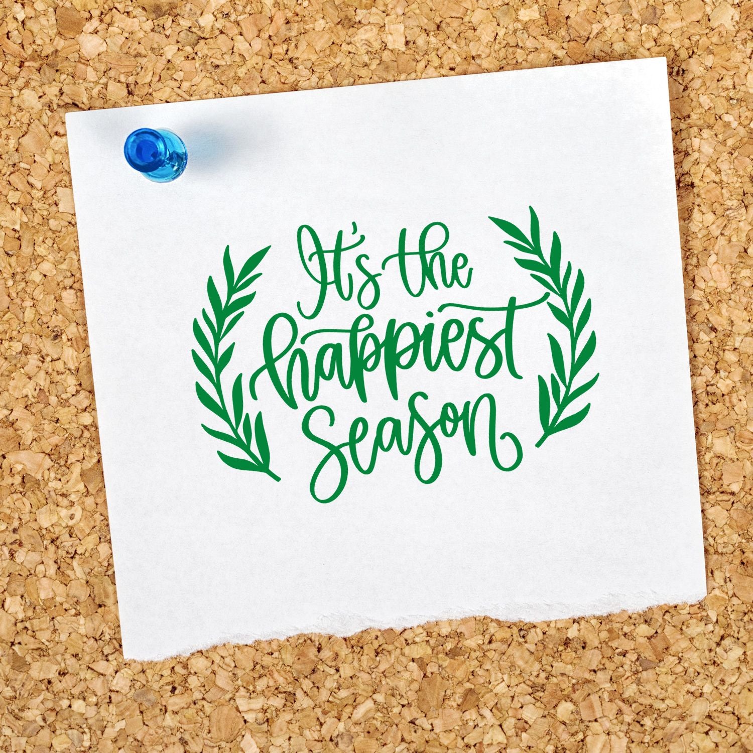 Holiday rubber stamp design with laurel wreath and green script reading Its the Happiest Season on pinned paper.