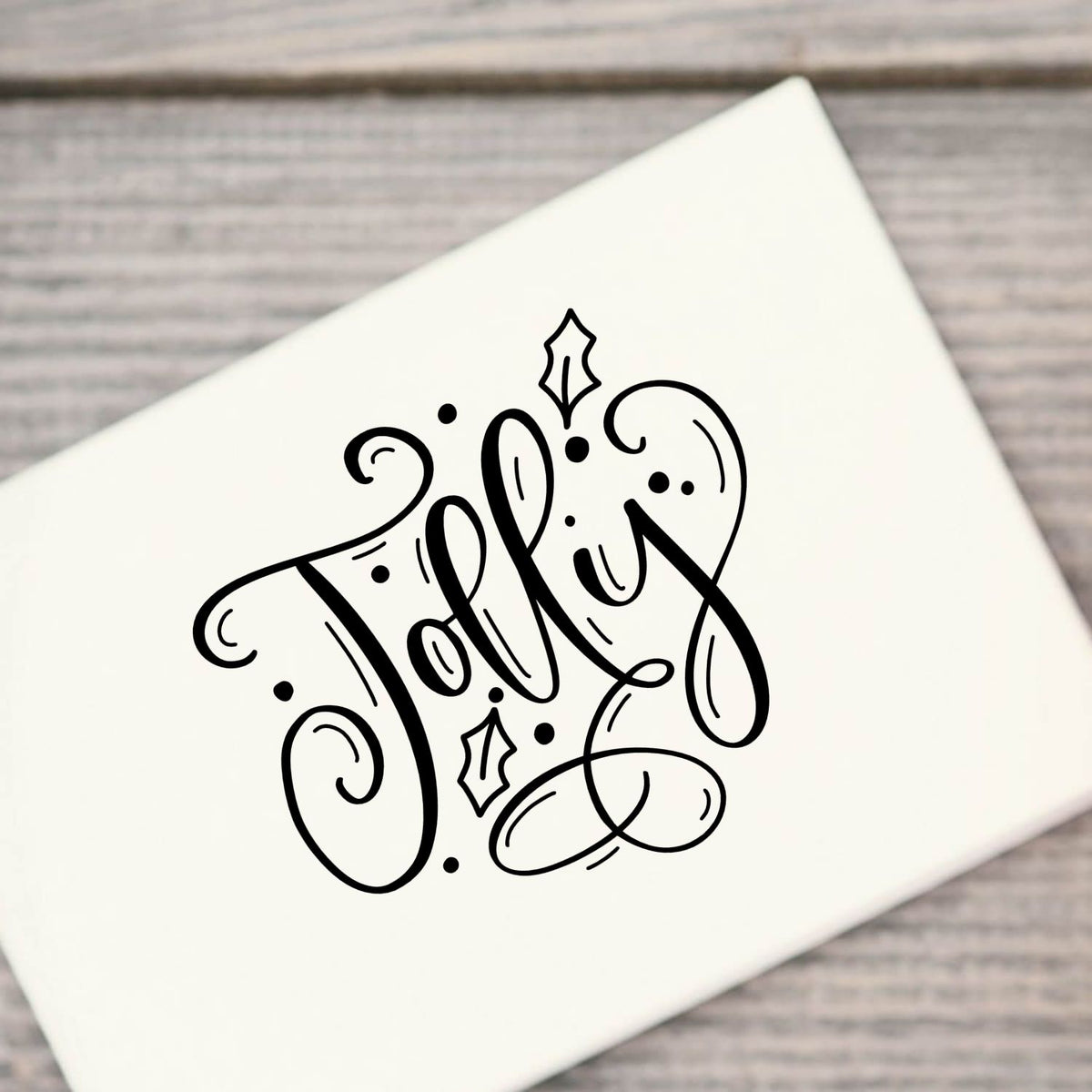 Jolly With Holly Premium Wooden Stamp - Vintage Pro imprint stamped in black ink. Large ornate script "Jolly" is decorated with holly leaves, dots, and looping flourishes.