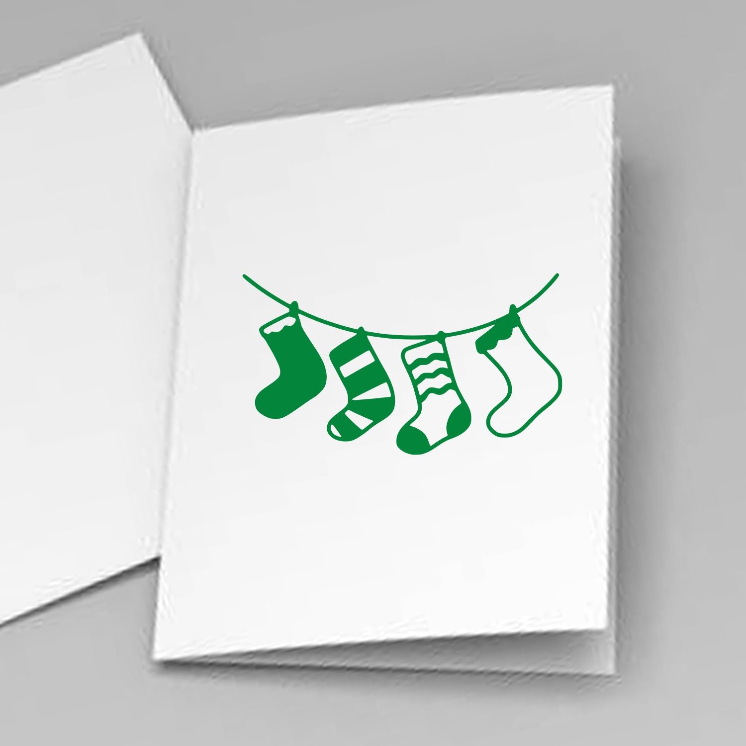 Four Christmas stockings hanging on a line rubber stamp design, ideal for holiday cards and seasonal craft projects.