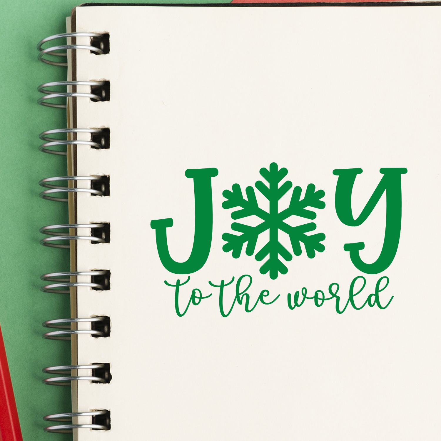 Joy to the World Christmas rubber stamp design with snowflake lettering on a spiral notebook page