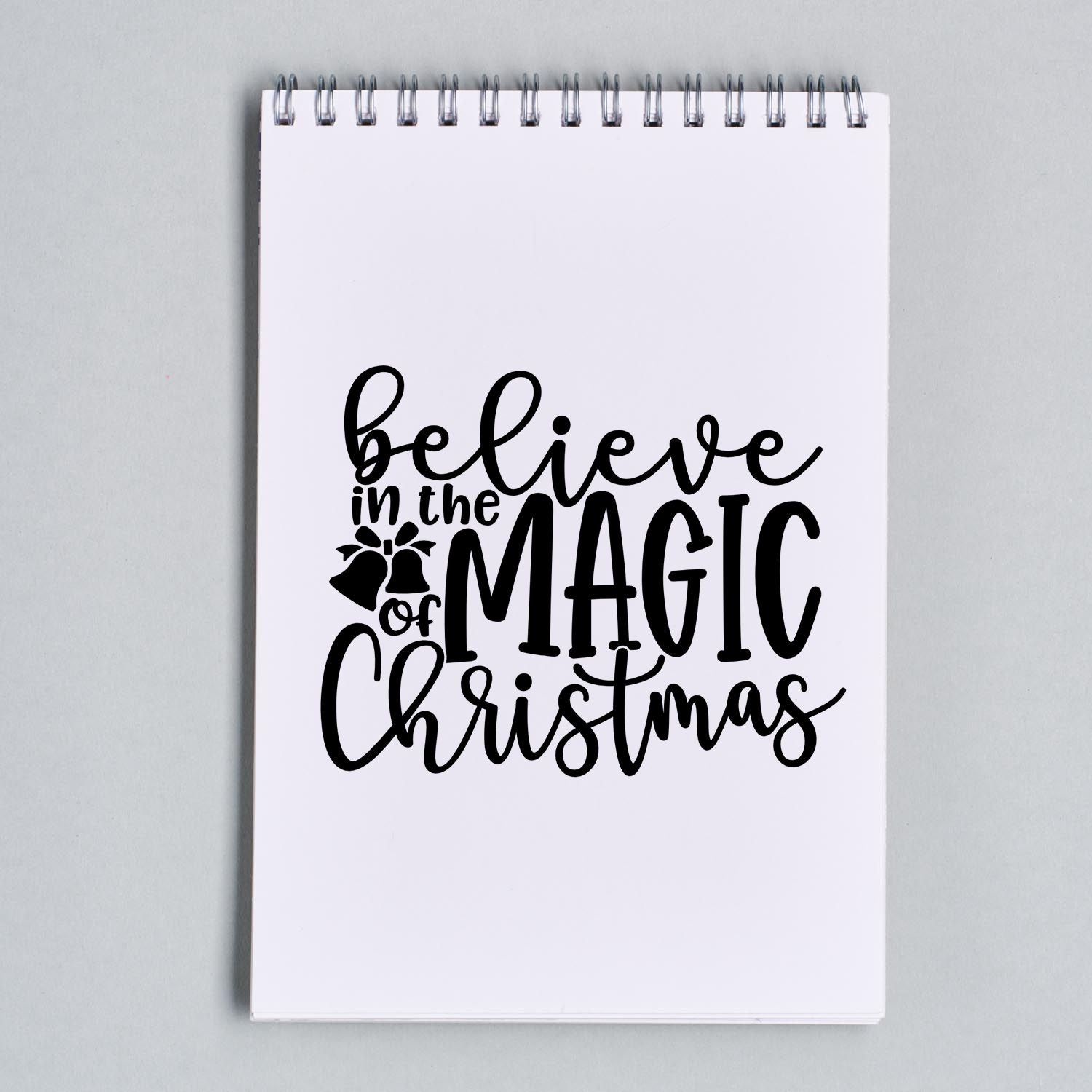 Believe in the Magic of Christmas rubber stamp design in black script on notebook page, perfect for festive holiday crafts and cards.
