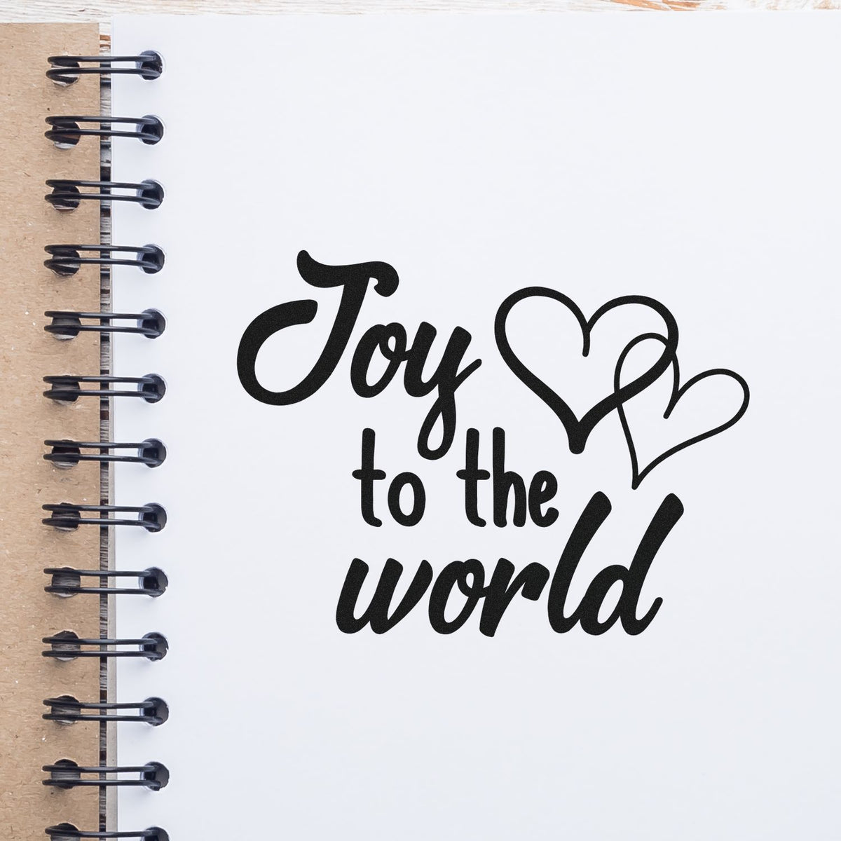 Joy To World Hearts Premium Wooden Stamp - Vintage Pro imprint stamped in black ink. "Joy to the World" appears beside two overlapping outlined hearts.