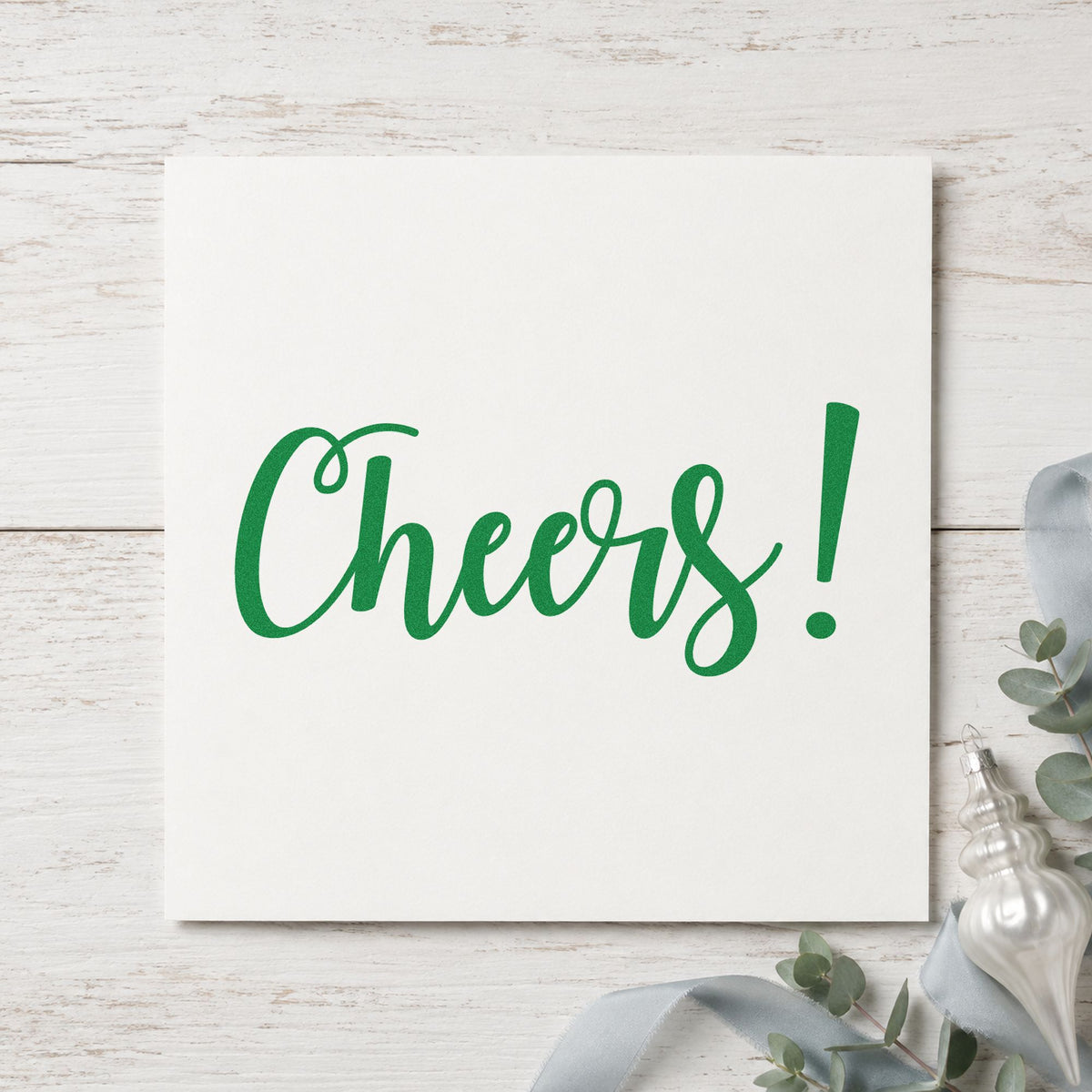 Cheers Flowing Script craft stamp imprint in green ink on a handmade project, one idea being glass charm tags.