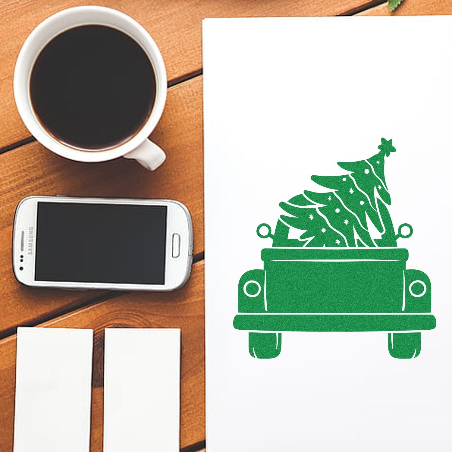 Holiday rubber stamp of a potted Christmas tree on paper, shown in a desk workspace for custom cards and crafts.