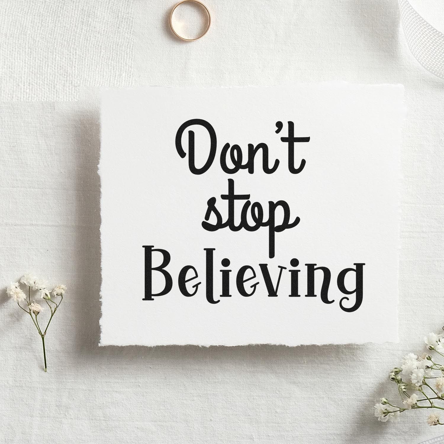 Inspirational quote rubber stamp reading Dont Stop Believing on white paper, perfect for handmade cards and craft projects.