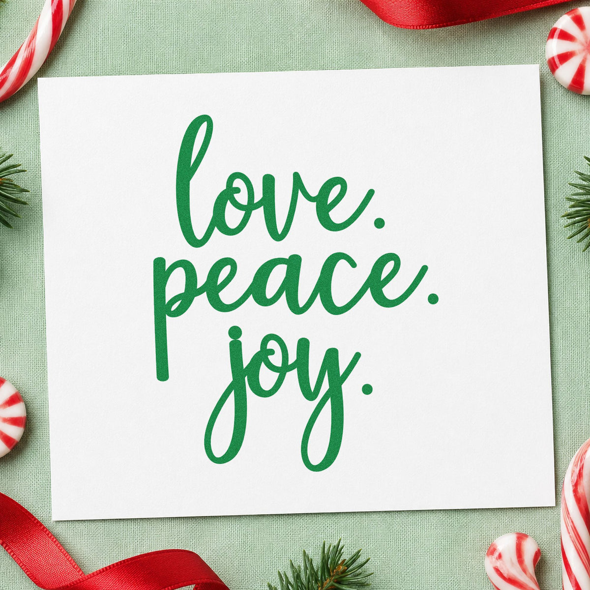 Love Peace Joy Script craft stamp imprinted in green ink on paper, a design suited to framed gallery row.