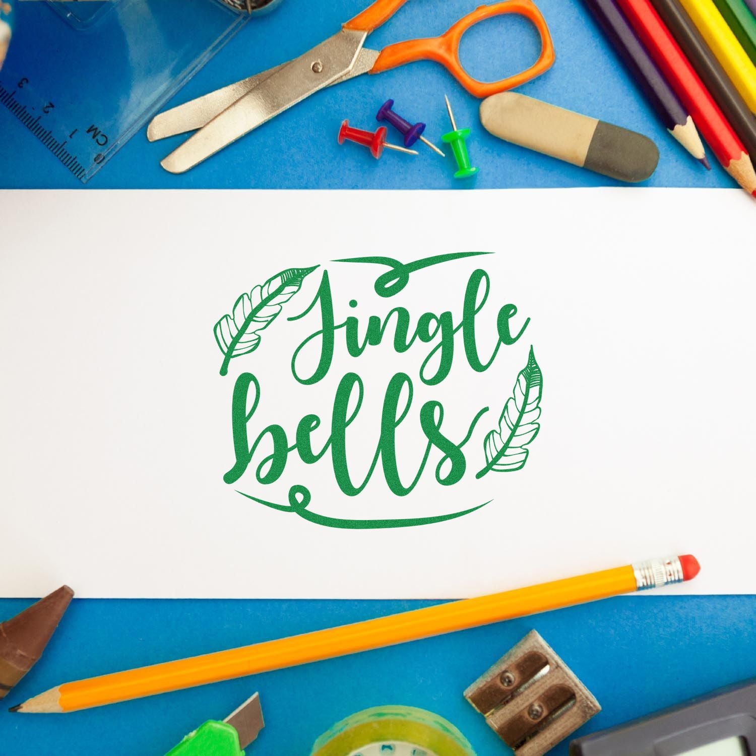 Jingle Bells holiday rubber stamp design for Christmas crafting, framed by school supplies on a blue background