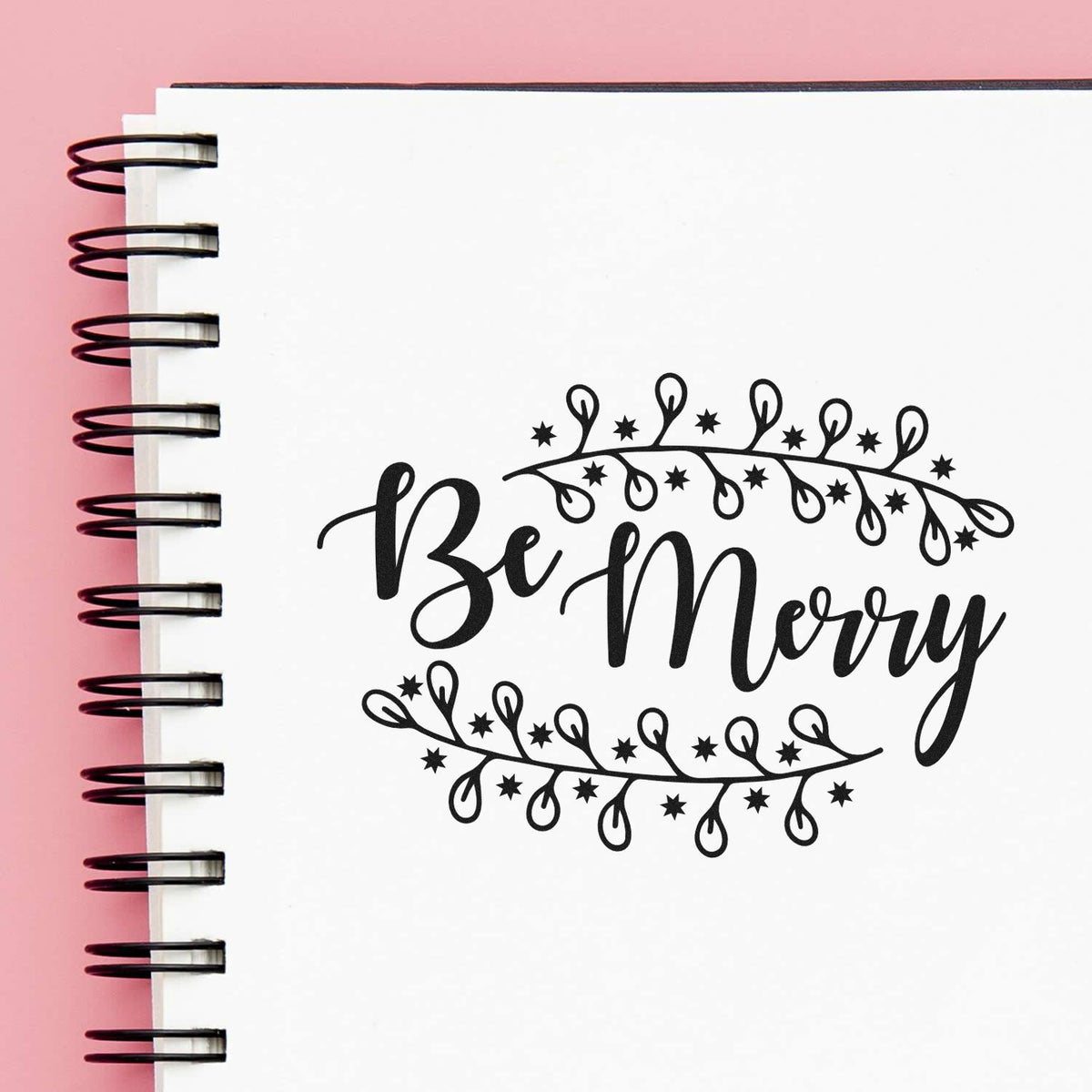 Premium Wooden Be Merry Botanical Border Stamp - Vintage Pro imprint stamped in black ink. "Be Merry" appears between curved branches of small leaves and buds.