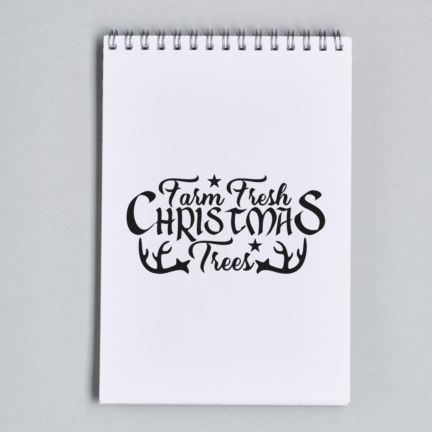 Farm Fresh Christmas Trees holiday rubber stamp design with antlers and stars on a blank notepad.