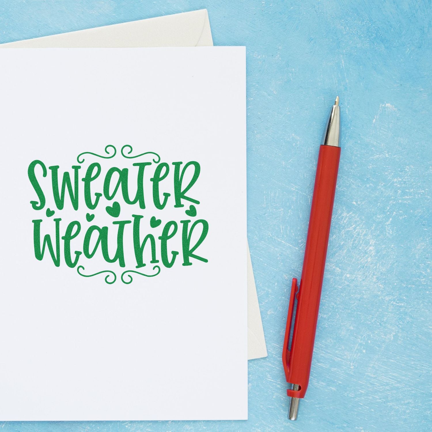 Sweater Weather rubber stamp for fall cards and handmade paper crafts, shown on a greeting card with pen.