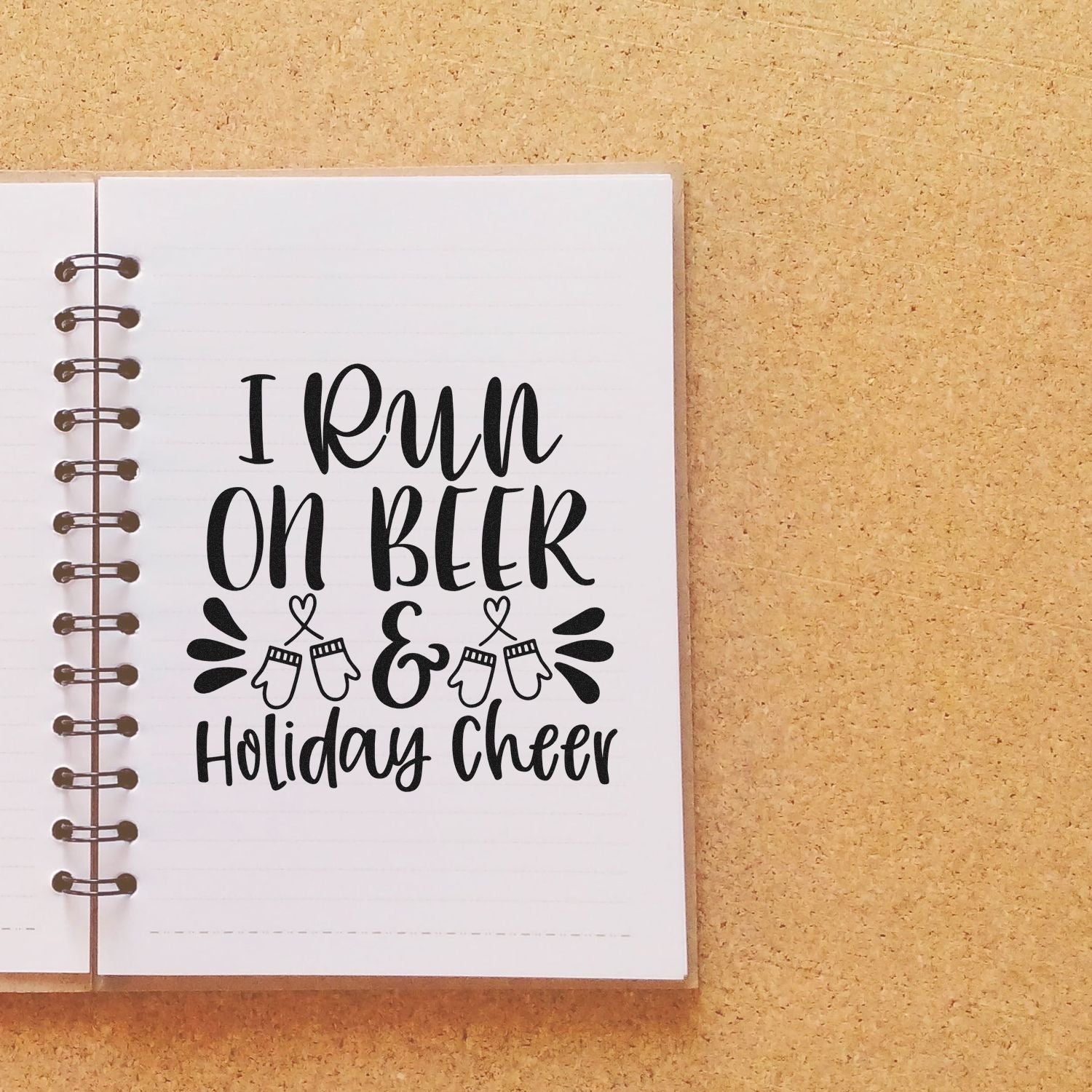 Holiday rubber stamp design reading I run on beer & holiday cheer in a notebook.