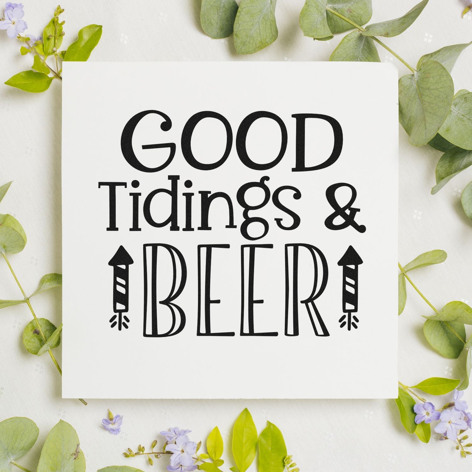 Holiday rubber stamp design reading Good Tidings & Beer with beer bottle icons on a white card with greenery.