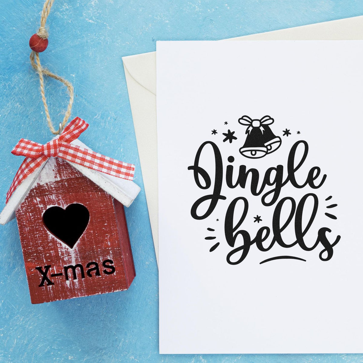 Jingle Bells Bow Bell Premium Wooden Stamp - Vintage Pro imprint stamped in black ink. "Jingle Bells" appears in thick script beneath a bow-topped bell with stars and accent rays.