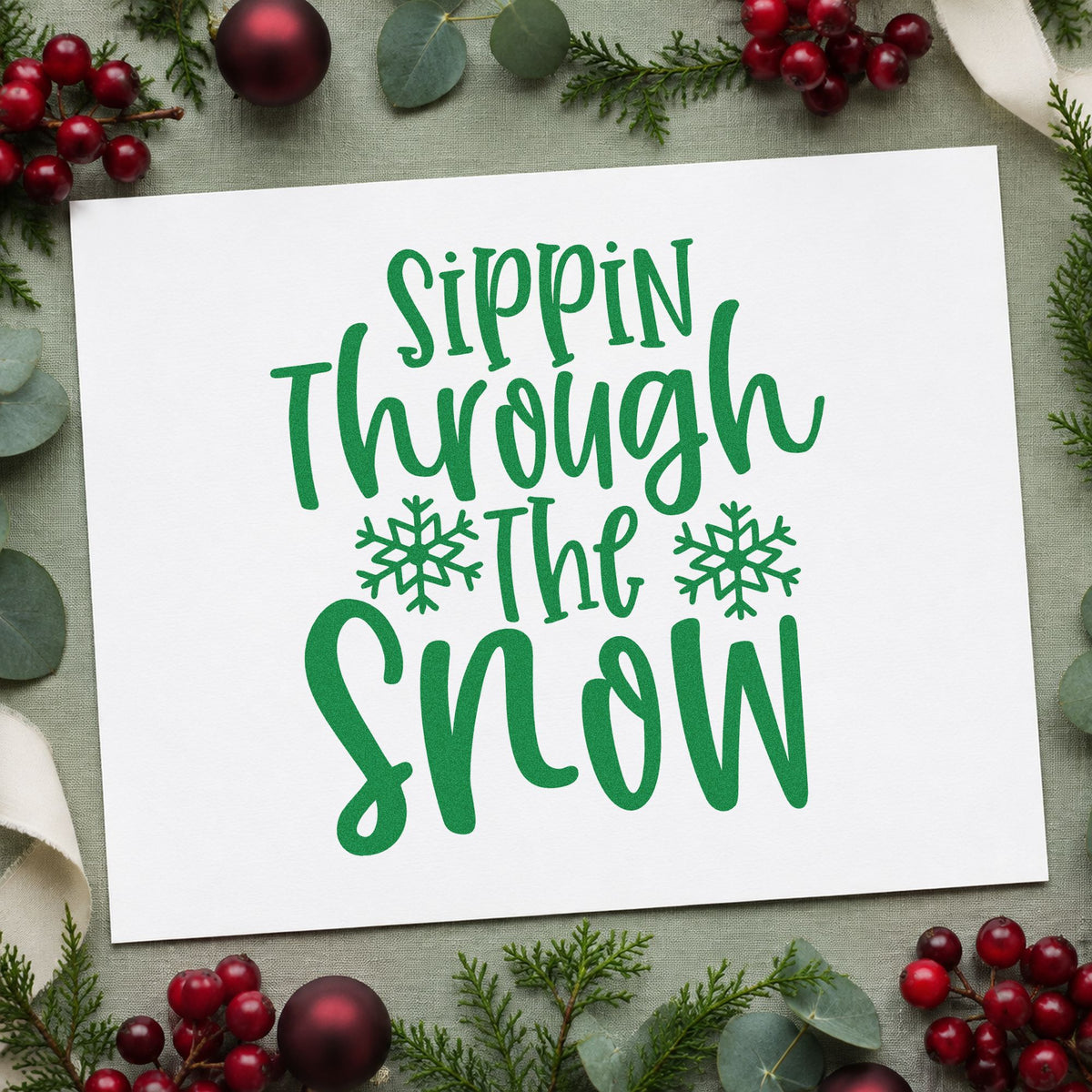 Sippin Through The Snow craft stamp imprint in green ink on a handmade project, one idea being tumbler gift tags.