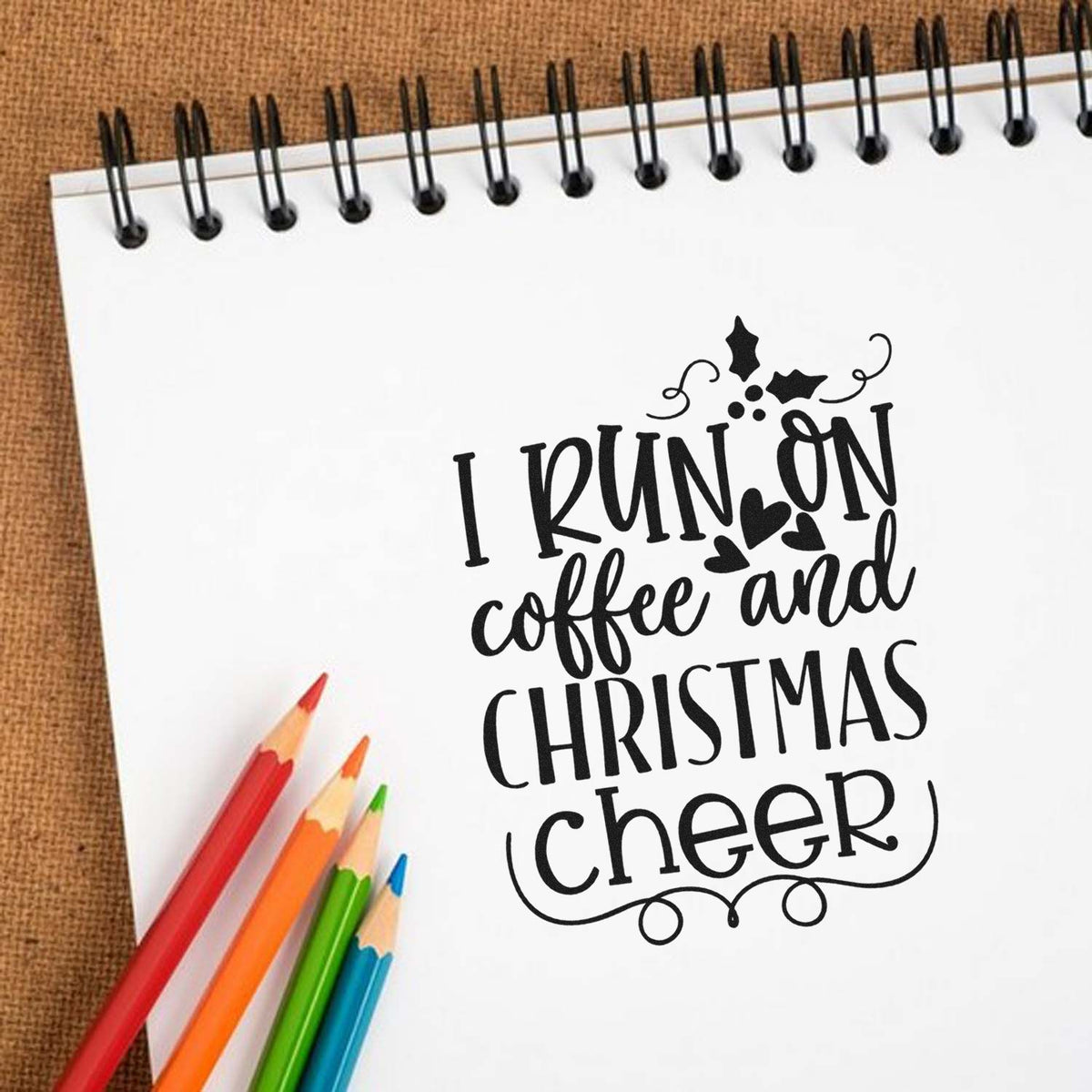 I Run On Coffee And Christmas Cheer Premium Wooden Stamp - Vintage Pro imprint stamped in black ink. The phrase "I run on coffee and Christmas cheer" is framed by holly and curling flourishes.