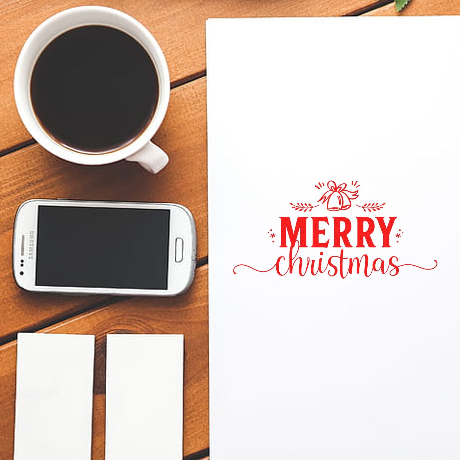 Merry Christmas rubber stamp impression on paper, styled for holiday card making with coffee cup and blank cards