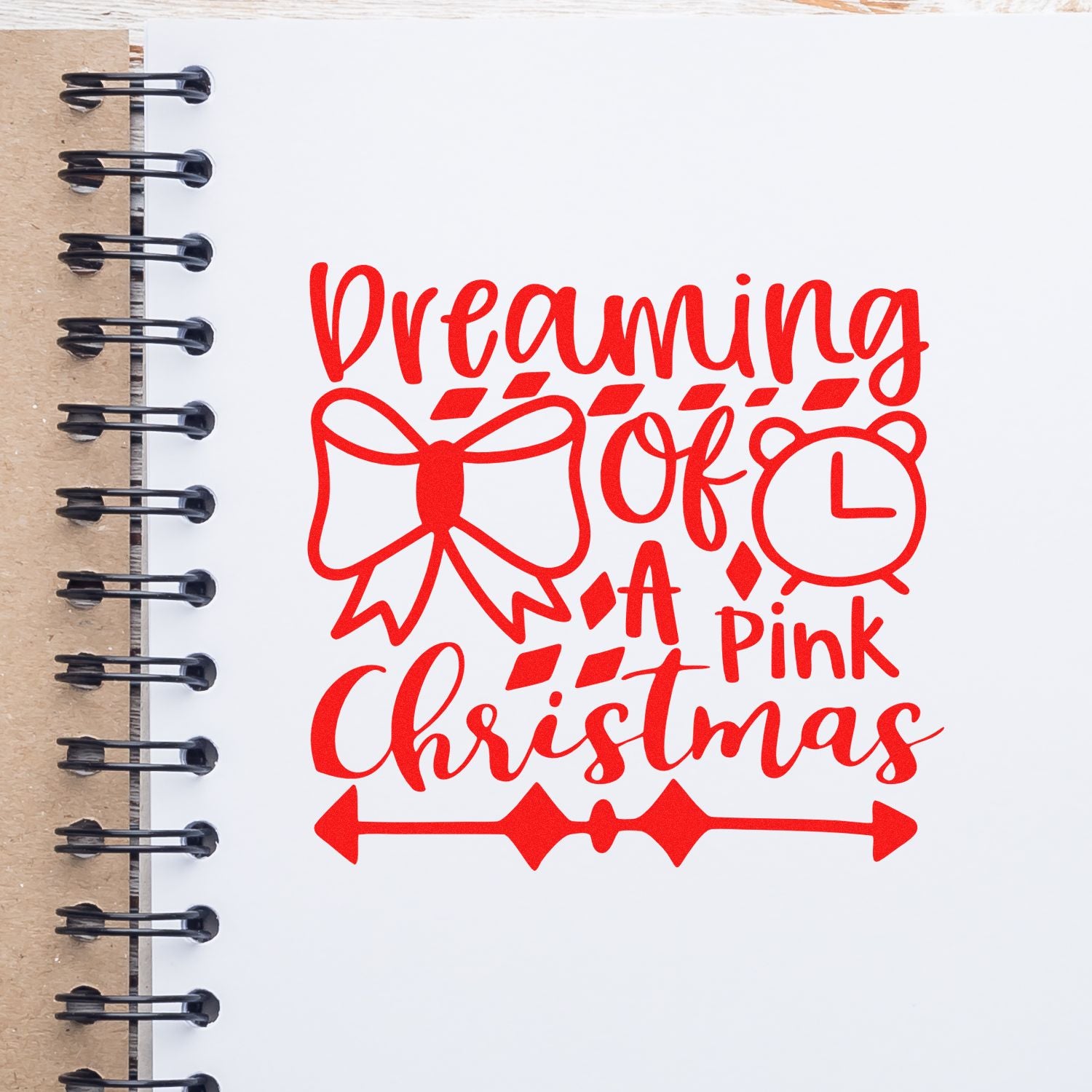 Dreaming of a Pink Christmas rubber stamp design with bow, clock, and festive holiday lettering on a notebook page.