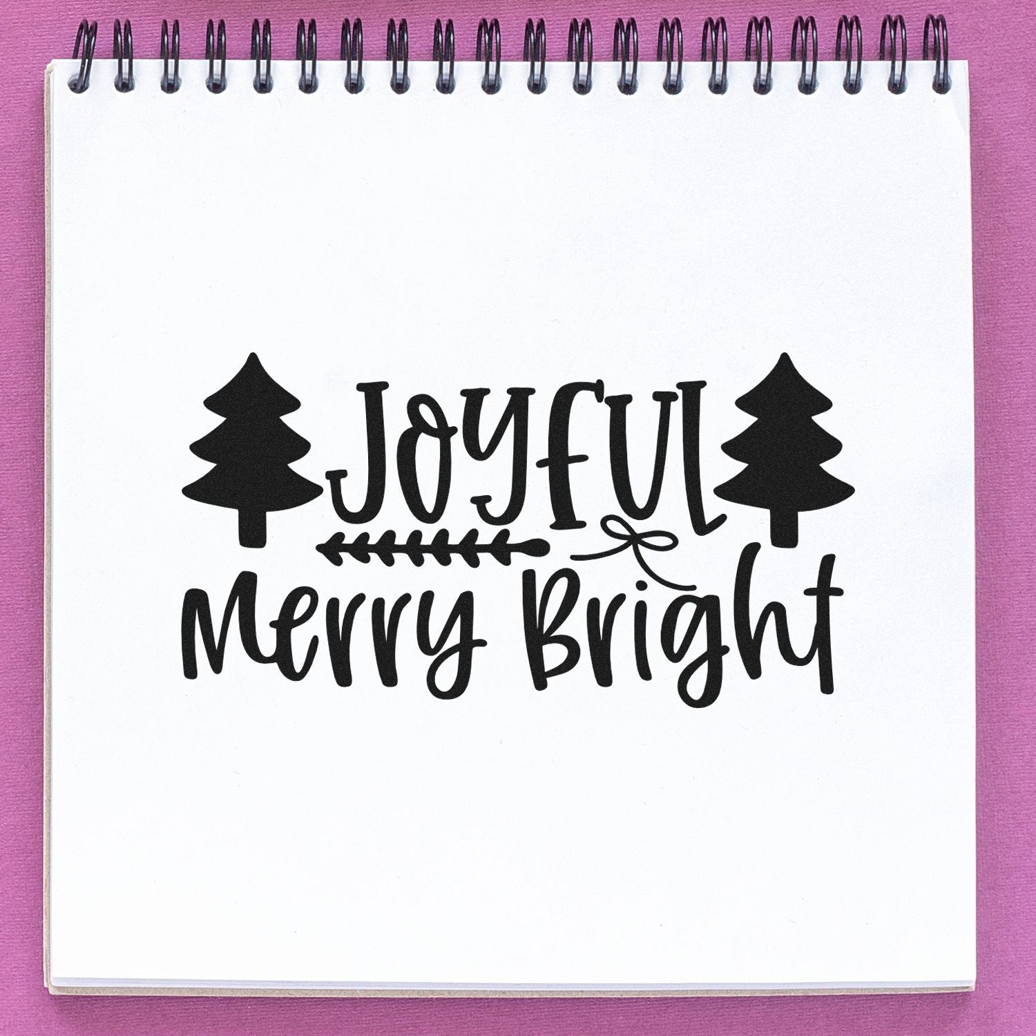 Joyful Merry Bright Christmas rubber stamp design with pine trees on a notebook page.