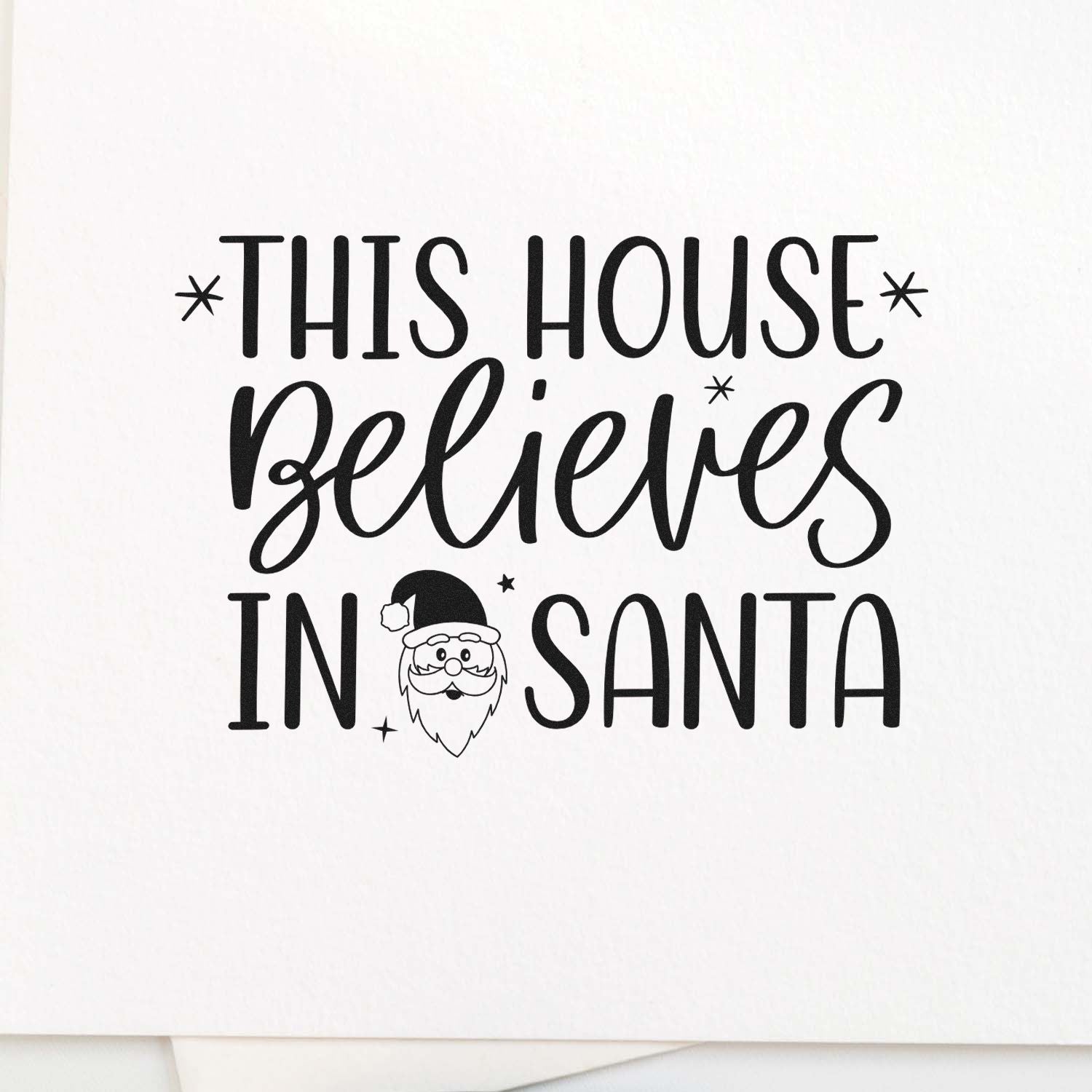 Christmas rubber stamp design reading This House Believes in Santa with Santa icon for holiday cards and crafts.