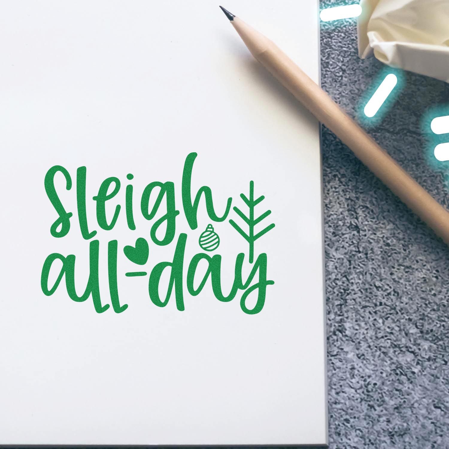 Green Sleigh All-Day Christmas rubber stamp design on a notebook, perfect for festive cards, gift tags, and holiday crafts.