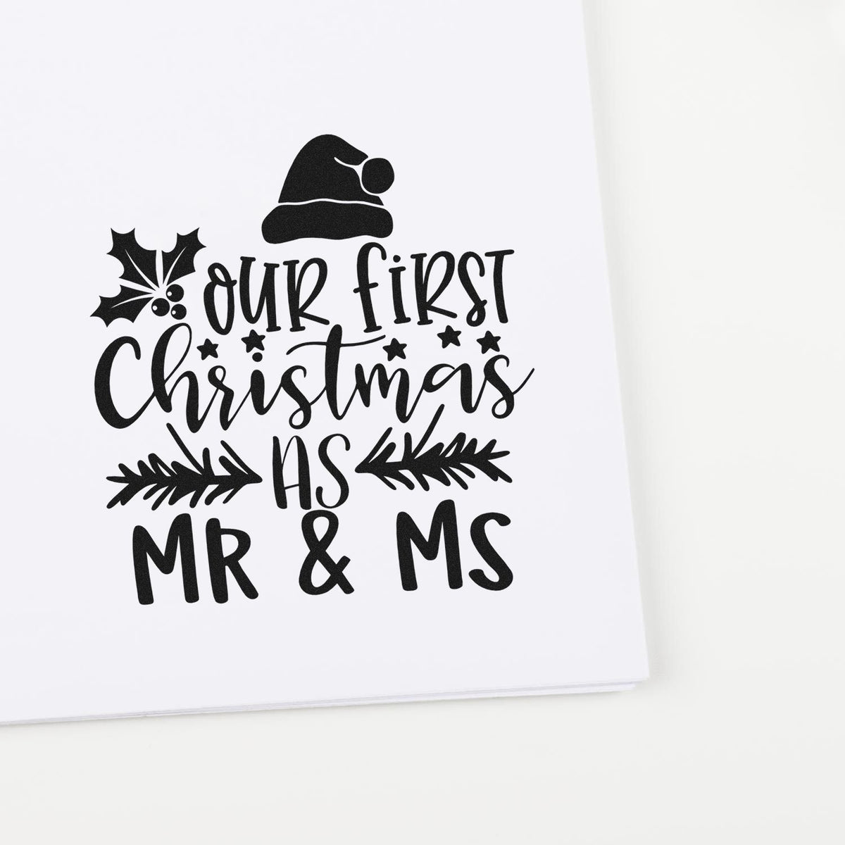 Our First Christmas As Mr & Ms Premium Wooden Stamp - Vintage Pro imprint stamped in black ink. The words "Our first Christmas as MR & MS" are decorated with holly, a Santa hat, stars, and evergreen sprigs.