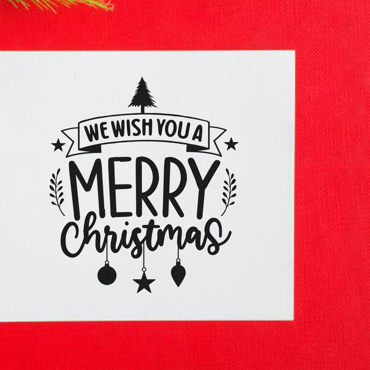 We Wish You Merry Christmas Premium Wooden Stamp - Vintage Pro imprint stamped in black ink. The words "We wish you a merry Christmas" include a banner, tree, stars, sprigs, and hanging ornaments.