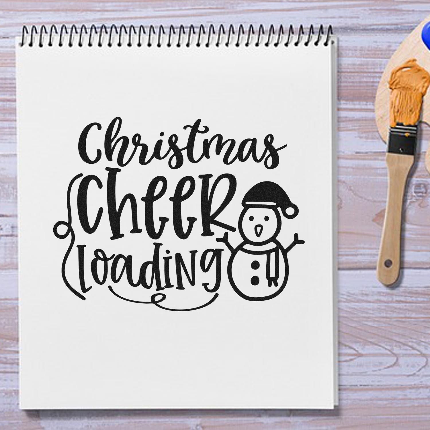 Christmas Cheer Loading rubber stamp design with snowman on notebook for holiday cards, scrapbooking, and festive crafts.