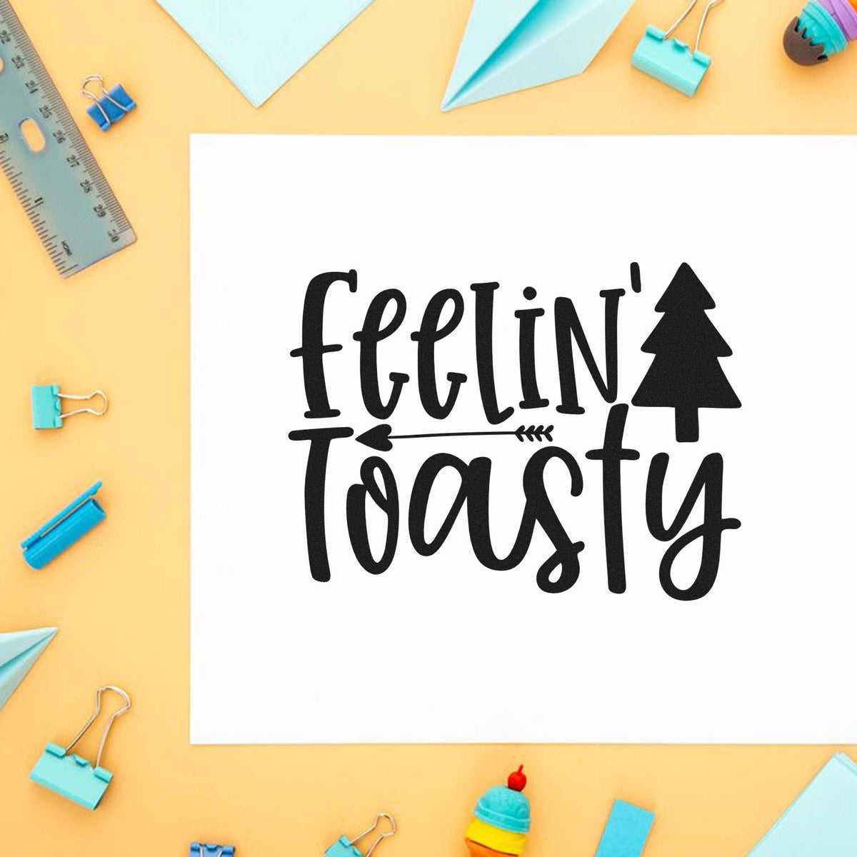 Feelin Toasty Christmas Tree Premium Wooden Stamp - Vintage Pro imprint stamped in black ink. The words "Feelin' toasty" appear with a solid Christmas tree and small arrow divider.