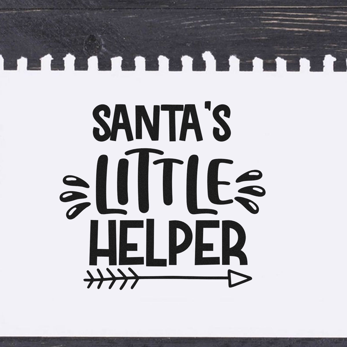 Vintage Pro Santa's Little Helper Arrow Premium Wooden Stamp imprint stamped in black ink. The words "Santa's little helper" appear above an outlined arrow with decorative splashes.