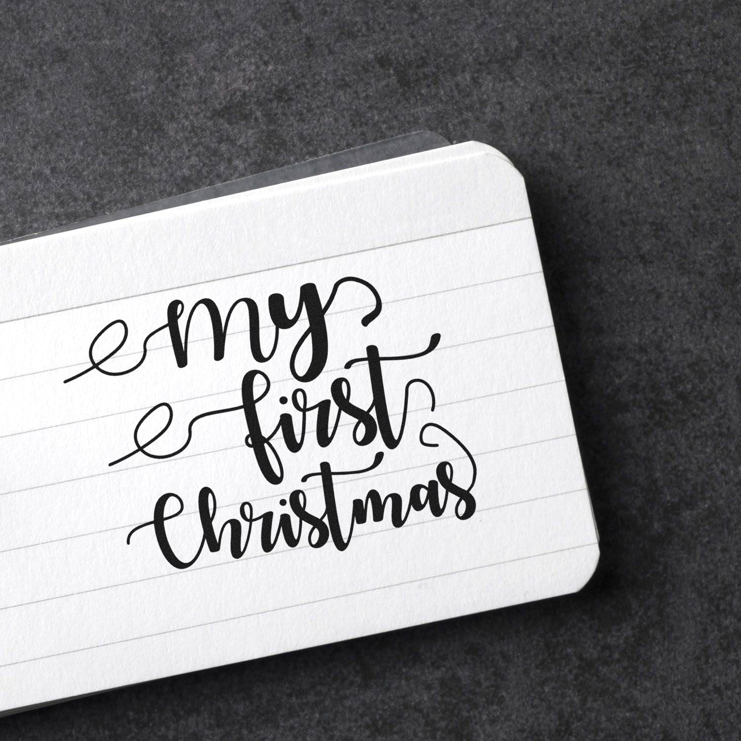 My First Christmas rubber stamp in script on lined paper, ideal for handmade holiday cards and festive scrapbook projects.