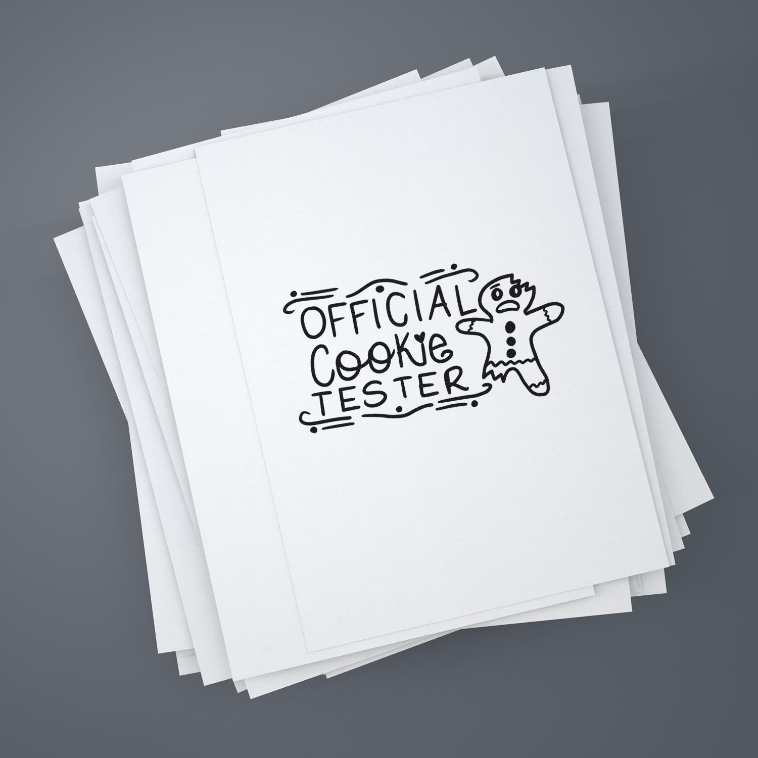 Custom rubber stamp design reading Official Cookie Tester with gingerbread man on stacked white paper sheets.