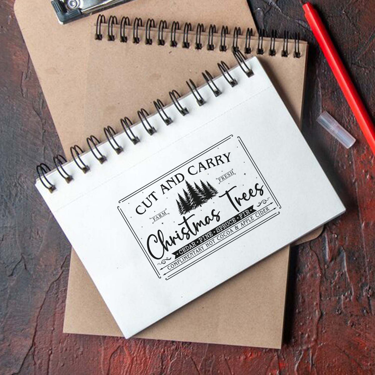 Cut And Carry Christmas Trees Premium Wooden Stamp - Vintage Pro imprint stamped in black ink. A framed vintage sign reads "Cut and carry Christmas trees" with pine trees, species names, and a cocoa-and-cider line.