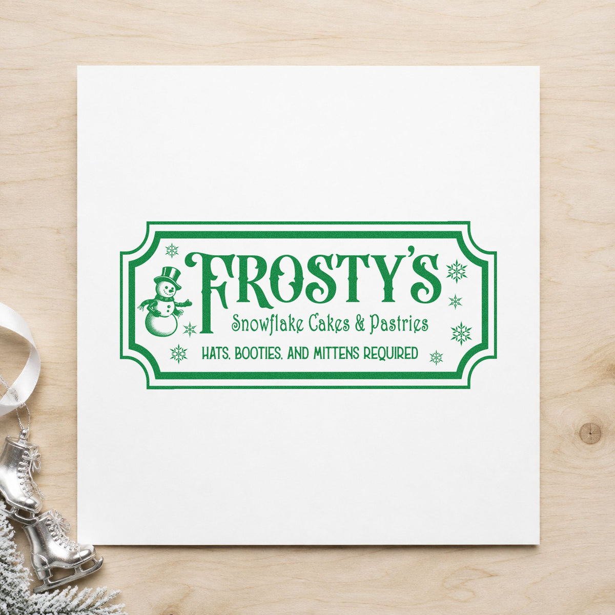 Frosty's Snowflake Cafe Pastries craft stamp imprinted in green ink on paper, a design suited to framed order counter.