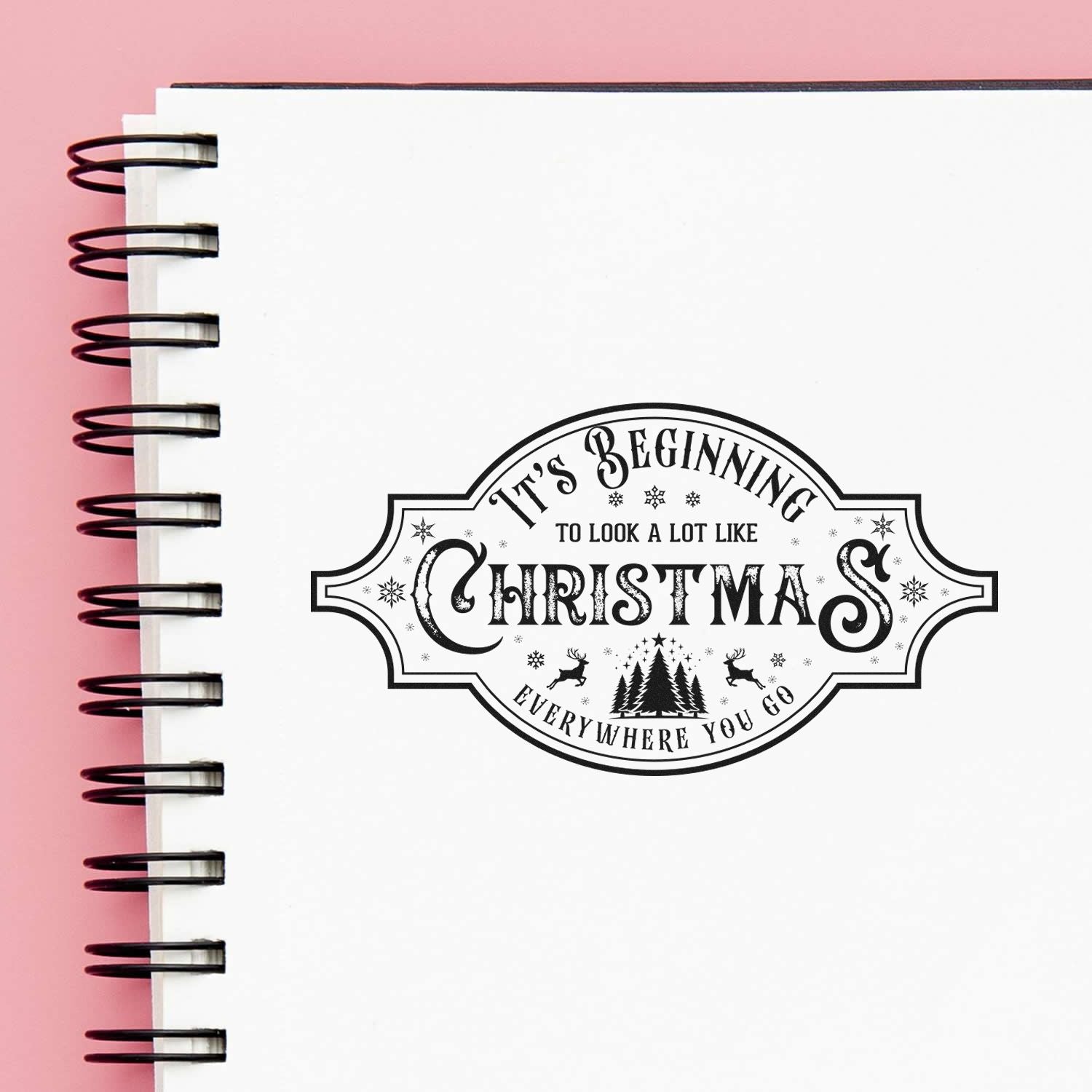 Holiday rubber stamp design in a notebook with Its Beginning to Look a Lot Like Christmas Everywhere You Go text.