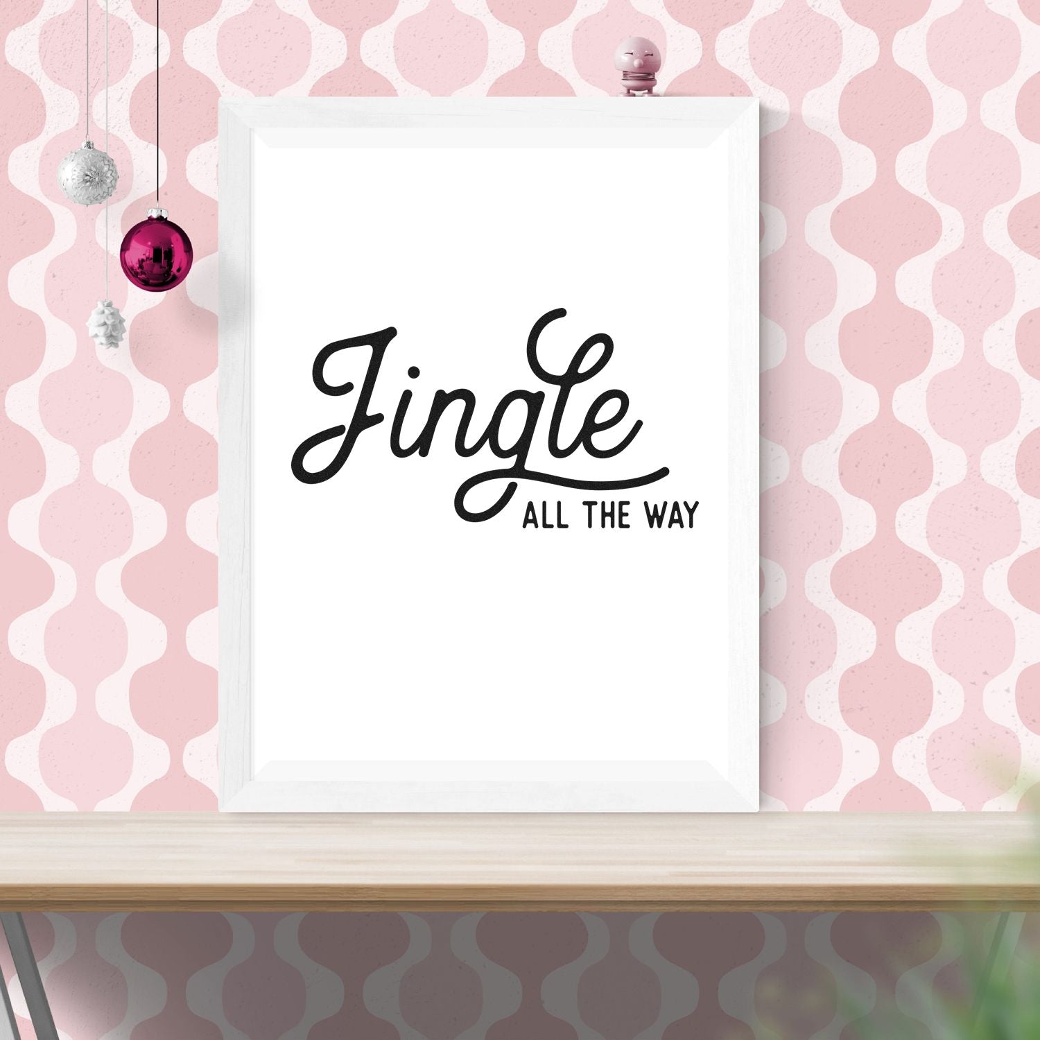 Jingle all the Way Christmas rubber stamp design mockup in script lettering on a framed print with pink holiday dcor.