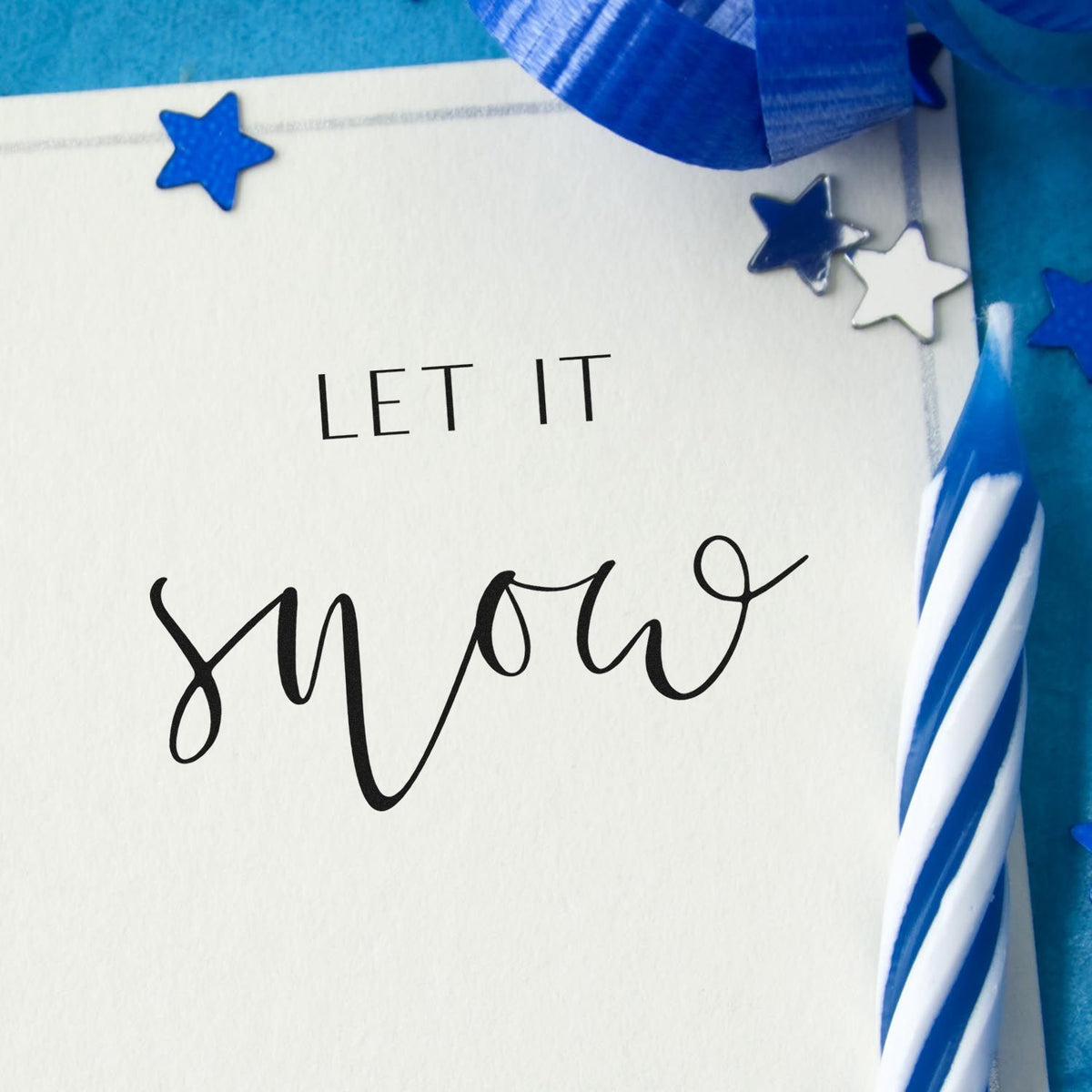 Let It Snow Fine Script Premium Wooden Stamp - Vintage Pro imprint stamped in black ink. The words "Let it snow" combine small plain capitals and a large airy script word.