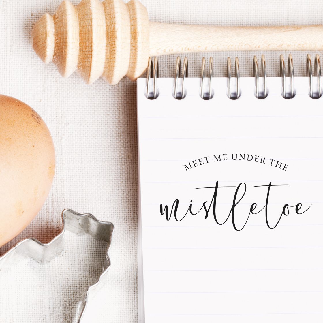 Meet Me Under Mistletoe Script Premium Wooden Stamp - Vintage Pro imprint stamped in brown ink. The phrase "Meet me under the mistletoe" features small arched capitals over a large fine script word.