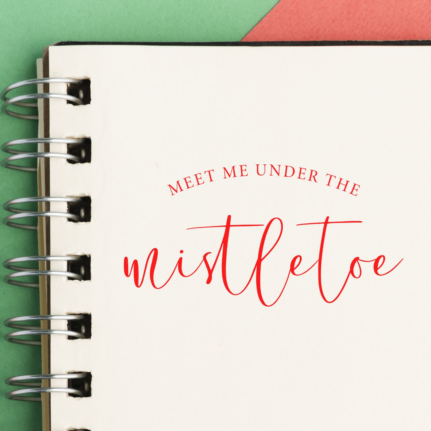 Christmas rubber stamp design reading Meet me under the mistletoe on a spiral notebook page.