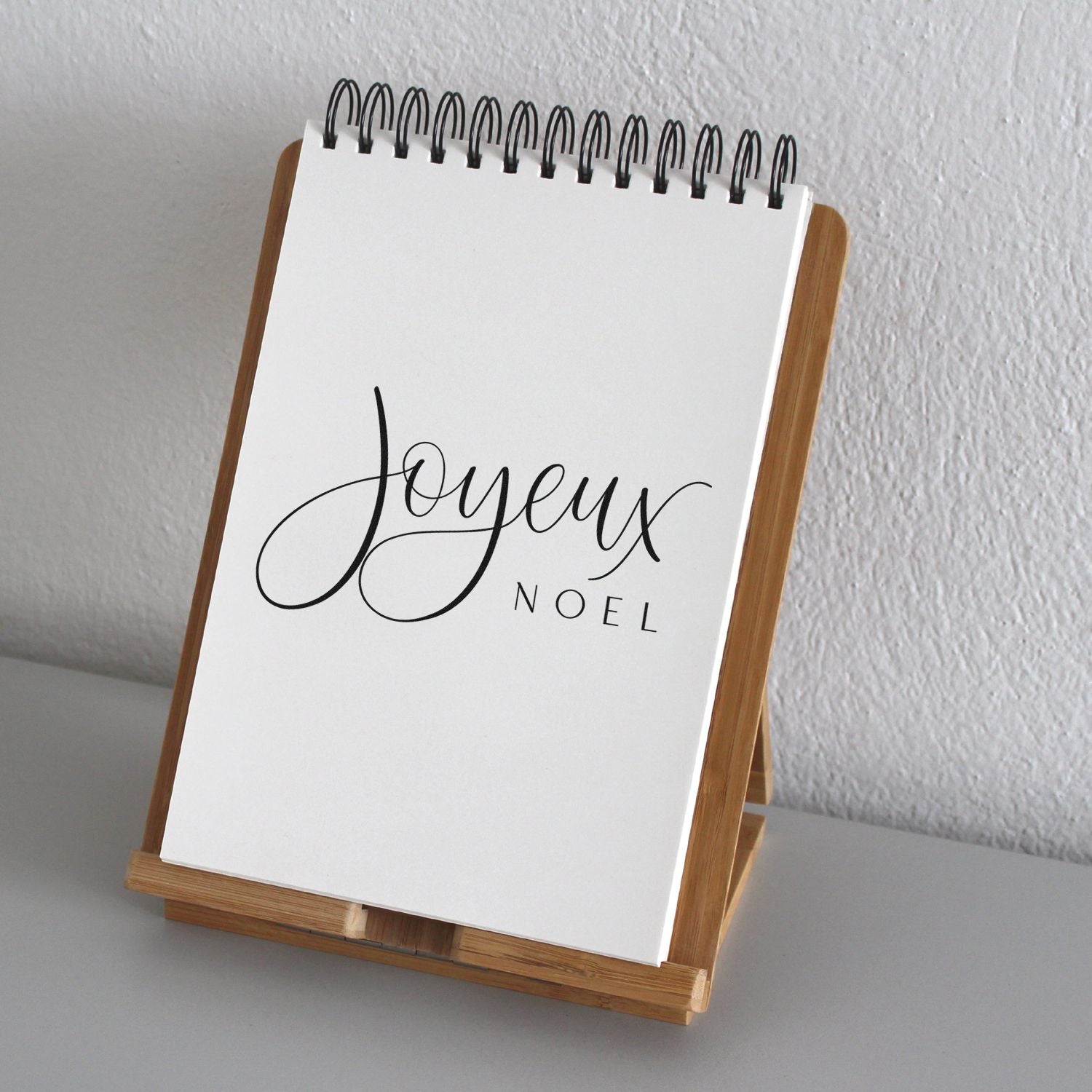 Joyeux Noel Christmas rubber stamp design on a spiral notebook display, perfect for holiday cards, tags, and festive stationery.