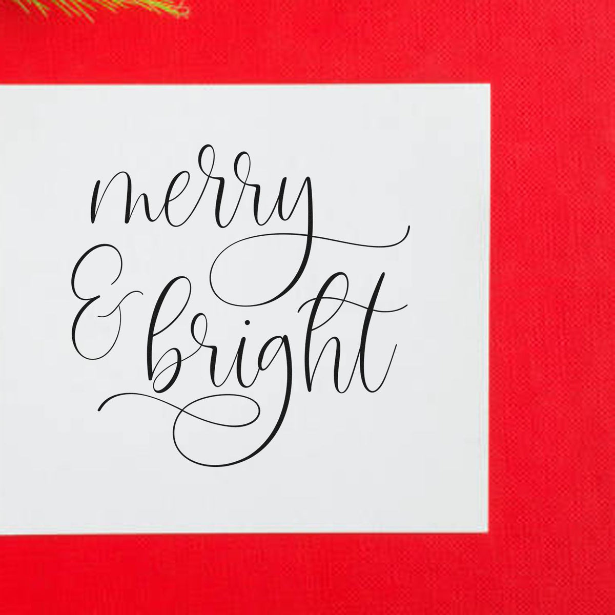 Merry And Bright Looped Script Premium Wooden Stamp - Vintage Pro imprint stamped in black ink. The words "merry & bright" appear in fine calligraphy with large looping flourishes.