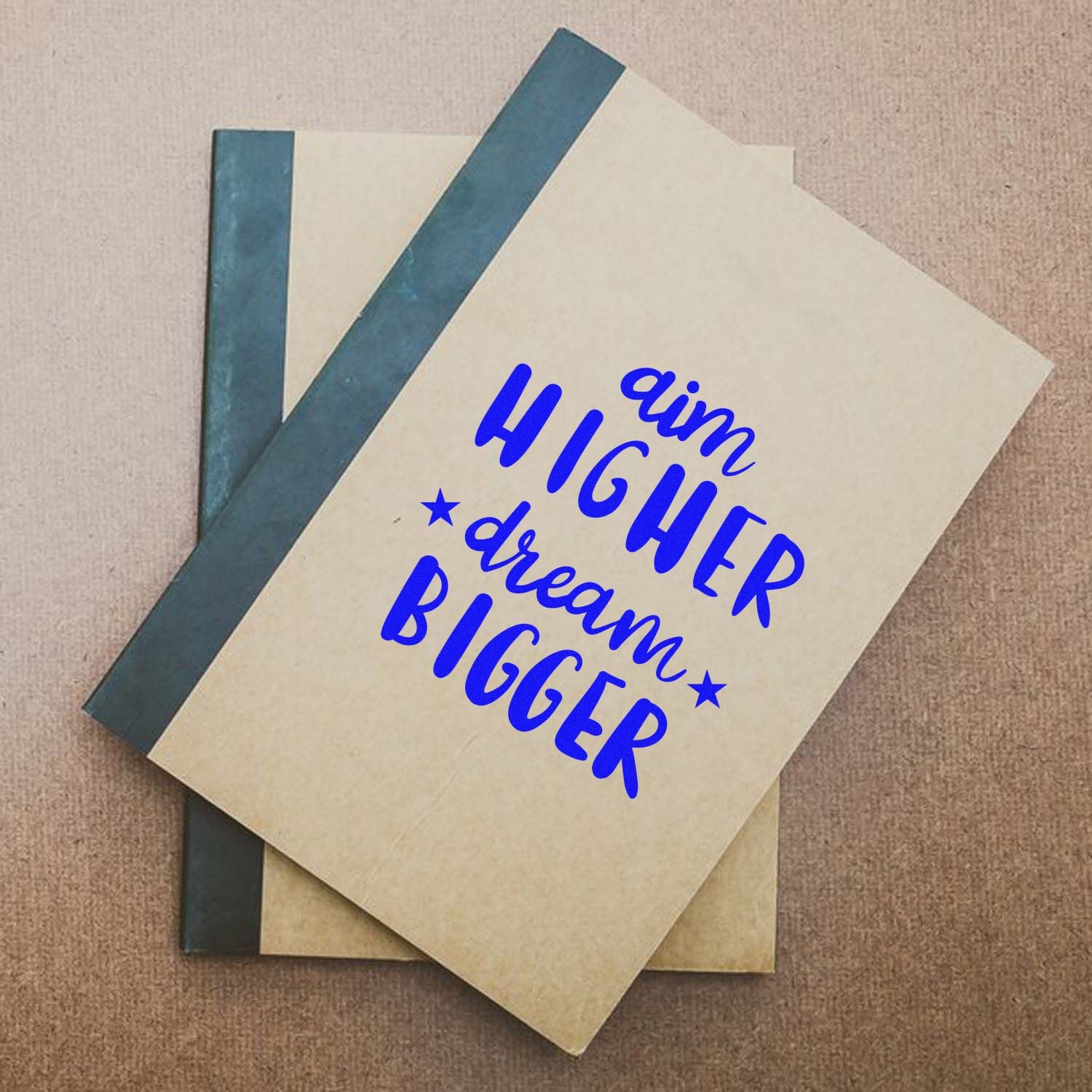 Custom rubber stamp on notebook cover with motivational quote Aim Higher, Dream Bigger for planners, journals, and gifts.