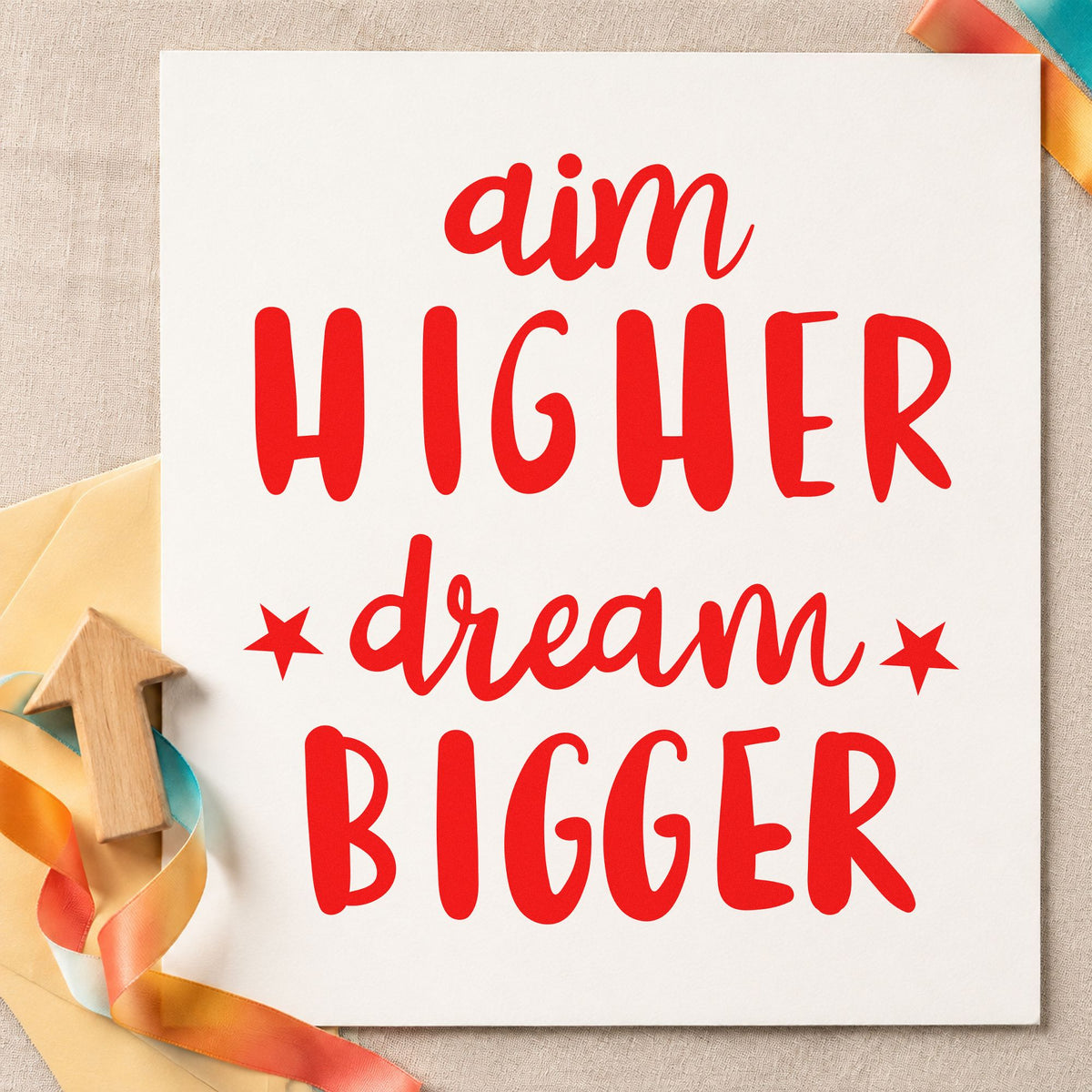 Aim Higher Dream Bigger craft stamp imprint in red ink on a handmade project, one idea being altitude goal cards.