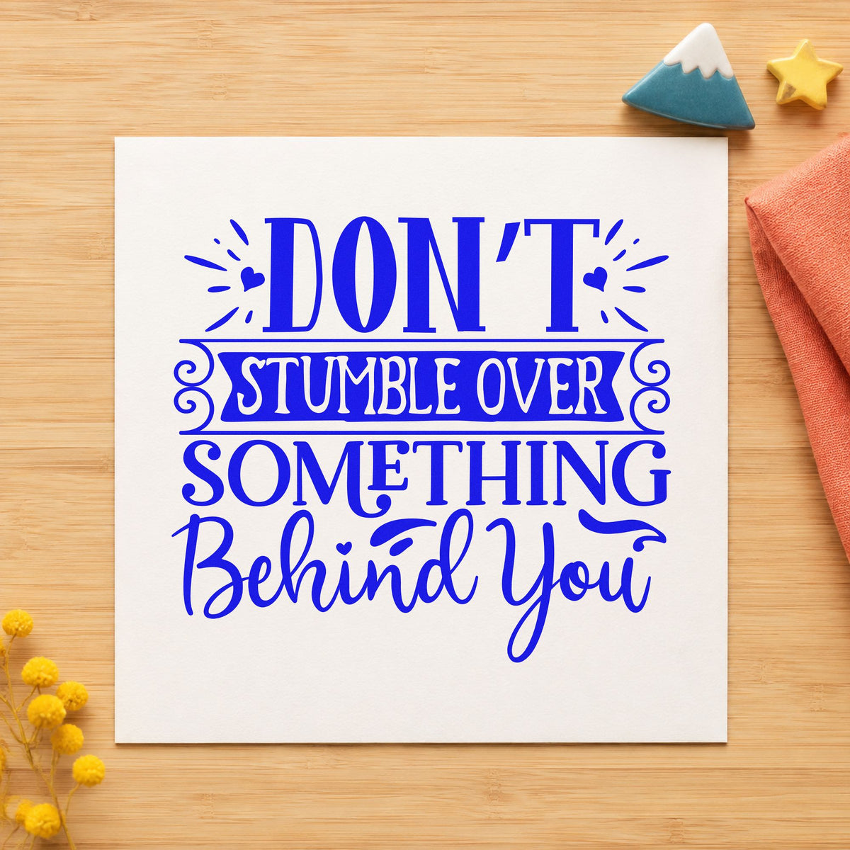 Don't Stumble Over Behind You craft stamp imprinted in blue ink on paper, a design suited to framed new entry.