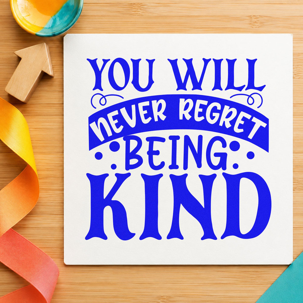 Never Regret Being Kind craft stamp in blue ink on cardstock, an easy option for barista apron printing.